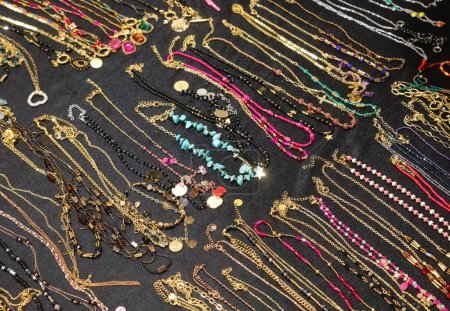 viele Halsketten und Armbänder und Fußkettchen für Frauen aus goldenem metallischem Material mit Edelsteinen oder Perlen und Anhängern zum Verkauf im Geschäft im Einkaufszentrum