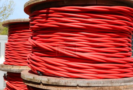Carretes de cable eléctrico rojo de alto voltaje que pueden transportar hasta 30000 voltios para conectar subestaciones eléctricas en la ciudad