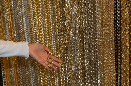 young woman  while choosing a golden chain to create a personalized necklace in the store