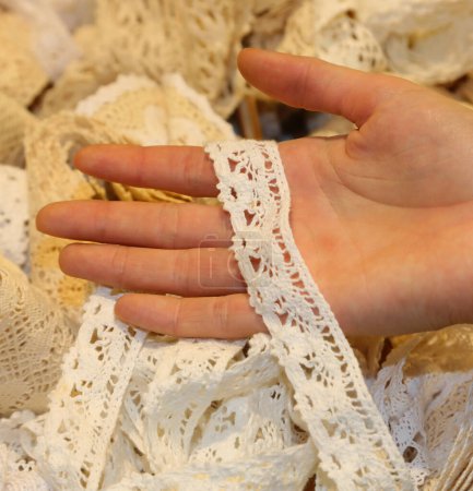 Jeune fille dentellière touchant le tissu brodé de lacets dans un atelier de tailleur artisanal