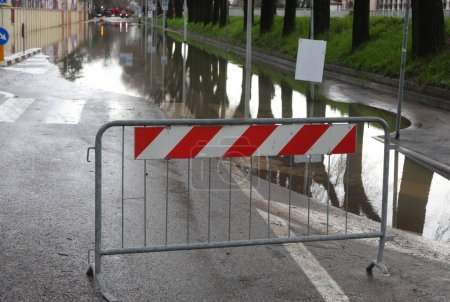 Barrera de carretera para cerrar la carretera al tráfico de vehículos porque la carretera está completamente inundada después de la inundación