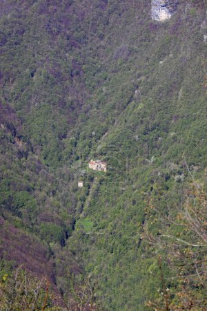 Anhäufung von ein paar Häusern in der verlorenen Landschaft inmitten der Wälder am Berghang