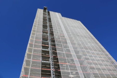 échafaudage du gigantesque gratte-ciel lors de la maintenance pour installer l'isolation thermique pour des économies d'énergie sans personnes