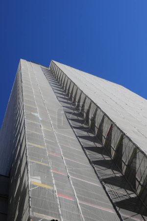 énorme échafaudage du gigantesque gratte-ciel lors de la maintenance pour installer l'isolation thermique pour des économies d'énergie sans personnes