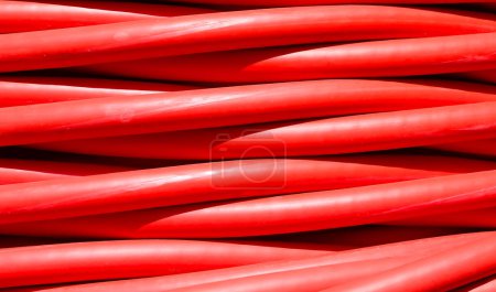 background of detailed thick red electrical cable used for high-voltage power transmission from a power plant to substations