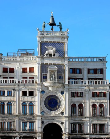 Venice, VE, Italy - February 13, 2024: Historical Palace with clock tower and two statues with bell on top called MORI DI VENEZIA and winged lion