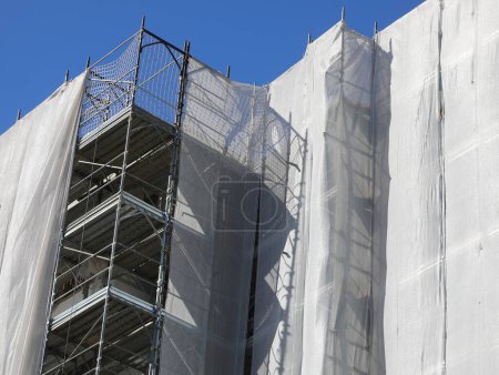 Photo for Detailed of residential building scaffolding during maintenance and installation of insulating panels to safeguard the environment and energy saving - Royalty Free Image