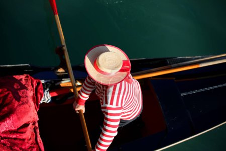 Foto de Gondolero en Venecia Italia con ropa típica veneciana y sombrero de paja grande mientras remaba en la góndola en el Gran Canal - Imagen libre de derechos