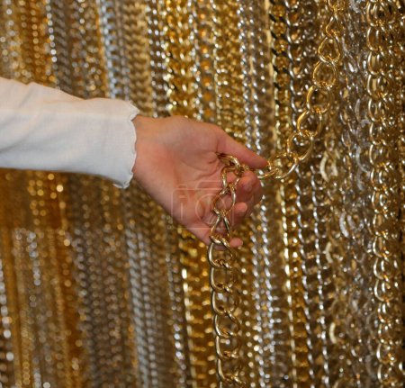 hand of a young girl while she is choosing a golden chain to create a personalized necklace in the mall store