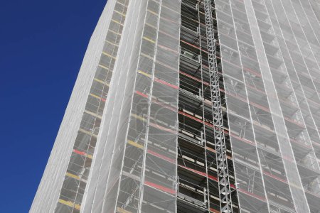 skyscraper with scaffolding during the installation of panels for thermo insulation