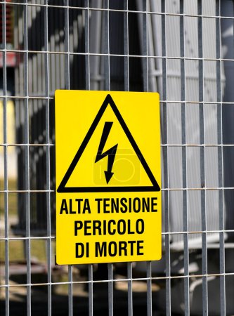 sign with the text high voltage danger of death in italian language with the triangle and the lightning outside the electrical substation