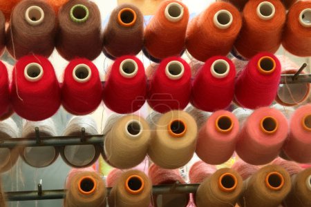 Téléchargez les photos : De nombreux rouleaux de tissu de différentes couleurs positionnés sur les étagères d'une usine de tricot artisanal avant le traitement - en image libre de droit