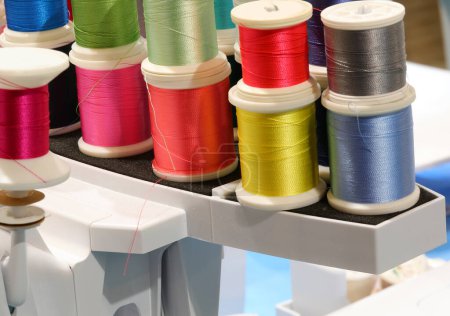 Téléchargez les photos : De nombreux fils de nombreuses couleurs pour la broderie et la couture dans la machine à coudre automatique très moderne - en image libre de droit