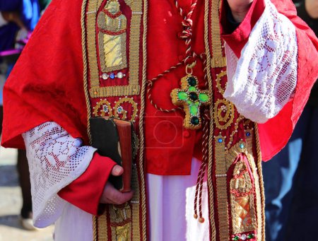 Téléchargez les photos : Prêtre avec robe religieuse rouge pendant la bénédiction avec la bible à la main - en image libre de droit