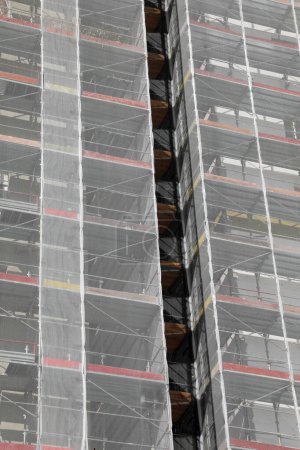 Thermal insulation and energy saving works on a tall skyscraper with apartments during the installation of the external thermal coat