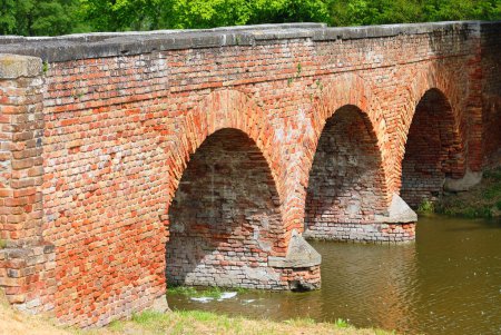Ancient bridge made of red bricks with three arches over the river