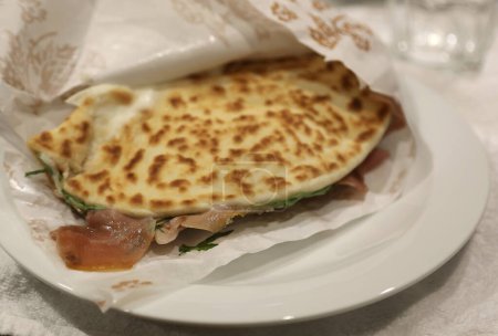 Foto de La típica comida italiana emiliana es la Piadina de peluche cocinada en un plato en el restaurante con jamón crudo y cohete - Imagen libre de derechos