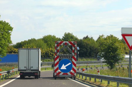 Foto de Camión de mantenimiento de la carretera con un letrero superior con una flecha enorme para señalar el estrechamiento del carril - Imagen libre de derechos