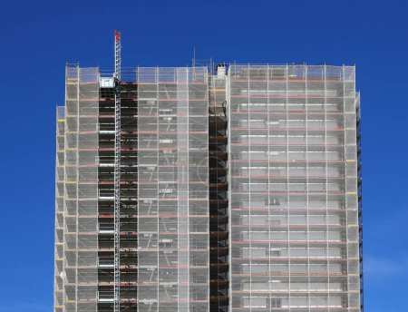 rascacielos con andamio de obra para la instalación de paneles aislantes para la reducción de residuos de recursos y eficiencia energética