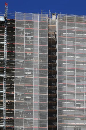 High-rise skyscraper with construction scaffolding for the installation of insulating panels to reduce energy consumption and save money