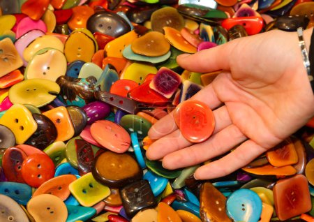 Téléchargez les photos : De nombreux boutons colorés créés à partir de la graine de la plante Tagua également connu sous le nom d'ivoire de légumes et donc éco-durable et une main de fille - en image libre de droit