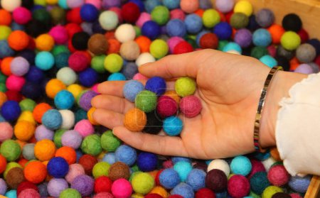 Foto de Mano de una joven con muchas bolas de colores hechas de lana hervida a la venta en la tienda de hobby ideal para hacer creaciones personalizadas - Imagen libre de derechos