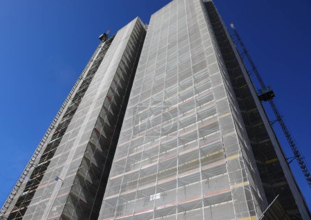 rascacielos con andamios para la instalación de paneles aislantes para reducir el consumo de energía y ahorrar dinero