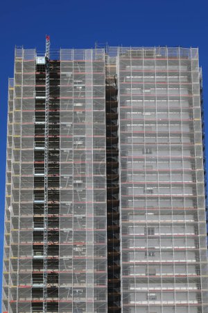 Scaffolding of skyscraper during maintenance and installation of insulation panels to safeguard the environment