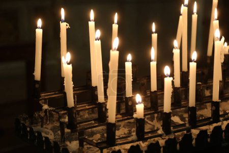 Religious lighting votive candles in a spiritual temple during a religious gathering
