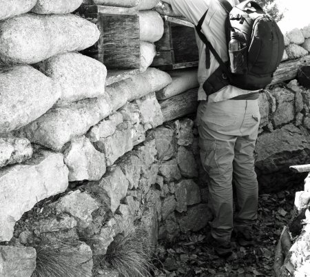soldier with black backpack inside the trench dug in the ground with black and white effect