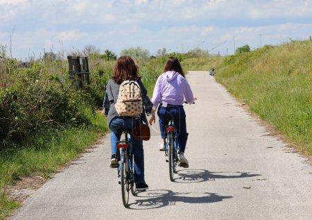 young girl with her mother cycling in the cycle path during the outdoor excursion