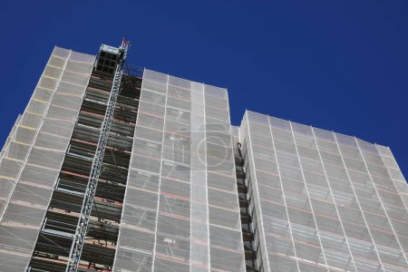 échafaudage d'un gratte-ciel lors de la maintenance pour installer l'isolation thermique à l'économie d'énergie vue d'en bas