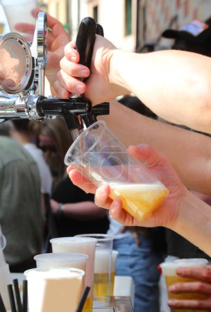 bartender s hand pours fresh draft beer into a glass during a village festiva