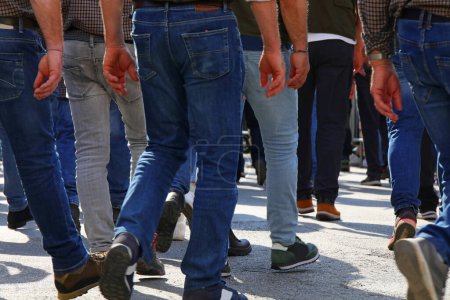 Crowd of men walking down the street with their jeans photographed behind them