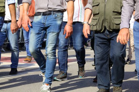 Jambes d'hommes marchant dans la rue en jeans pendant une parate avec leurs visages invisibles