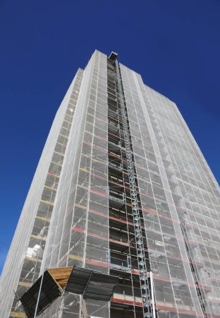 Scaffolding of skyscraper during maintenance and installation of insulation panels to safeguard the environment and energy saving