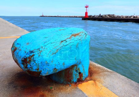large bollard that serves to securely moor ships to the port and a lighthouse in the background