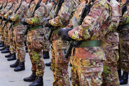 peloton de soldats en uniforme de camouflage debout à l'attention avec fusils d'assaut et bottes de combat