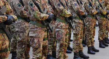 soldados con uniformes de camuflaje de pie a la atención con rifles de asalto