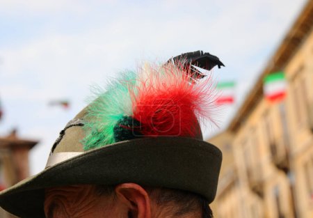 Kopf einer Person mit einem für Alpini typischen schwarzen Federhut der Gebirgstruppen der italienischen Armee und mit einer Trikolore-Verzierung in den Farben der italienischen Flagge