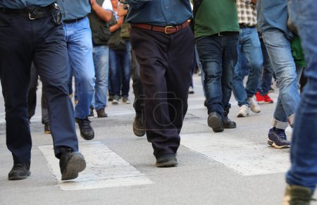 Beine vieler Männer, die in Jeans die Straße hinunterlaufen und ihr Gesicht nicht sehen