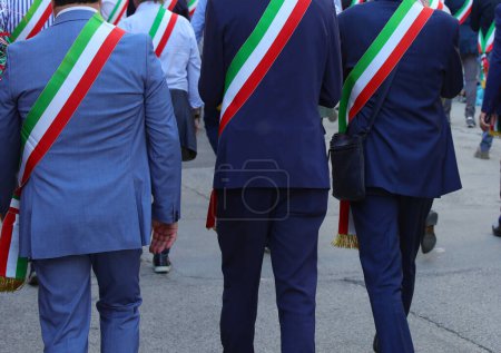 Italian mayors walking on the street with the tricolor sash of the Italian flag during the parade through the city streets
