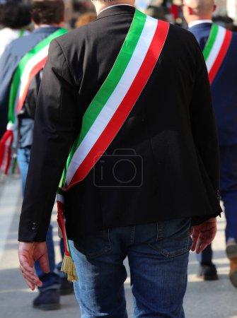 Italian mayors walking on the street with the tricolor sash of Italian flag during the parade through the city streets