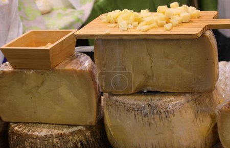 Cheese counter with many fresh or mature cheeses for sale in wheels or slices and a tasting platter