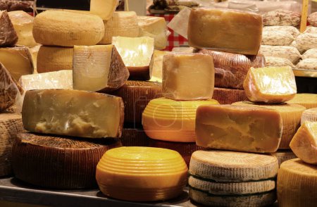 Cheese counter with many aged cheeses for sale in wheels or pieces