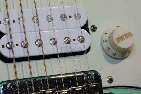 Close-up of an electric guitar with pickups and volume knob