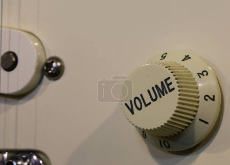 détail du bouton de volume avec le texte gravé et le pickpu de la guitare électrique vintage usagée en bois blanc