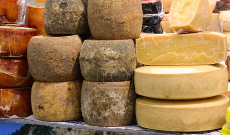 Cheese counter with many fresh or mature cheeses for sale in wheels or slices