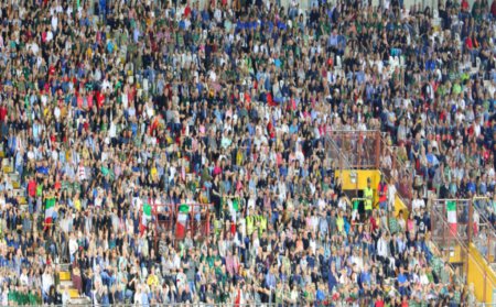 Blurred background of a large crowd of unrecognizable faces in the packed stadium stands during the event