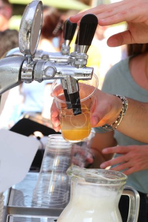 Busy bartender pouring a glass of fresh lager beer during outdoor party